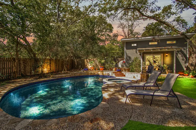 Twilight pool and spa with lit house behind, warm sky reflected in water. — San Antonio real estate photography