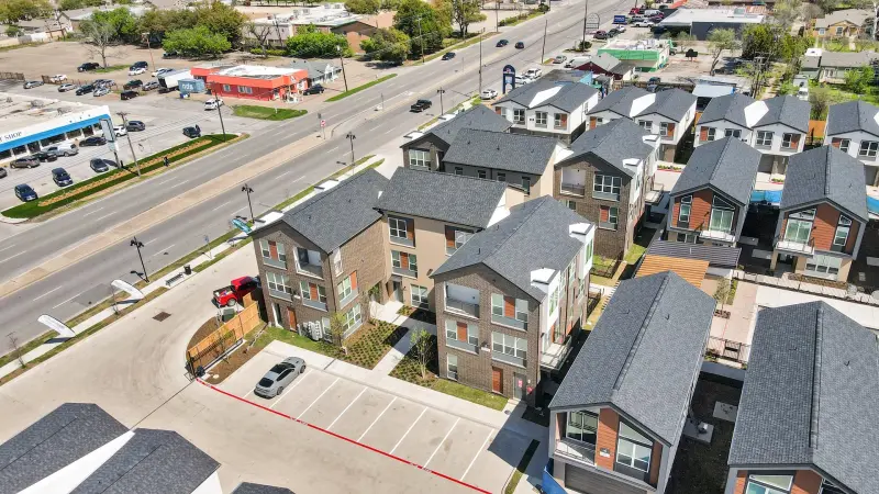 Aerial of modern townhome community with streets and parking (labeled bedroom). Decent context drone shot. — Dallas/Fort Worth real estate photography