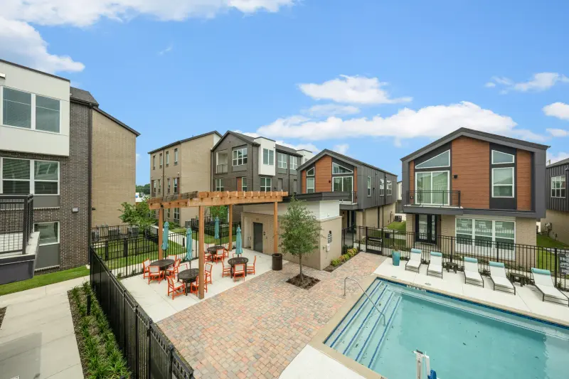 Community courtyard amenity: pool, pergola, orange cafe seating, modern townhomes, big sky. Strong commercial frame. — Dallas/Fort Worth real estate photography