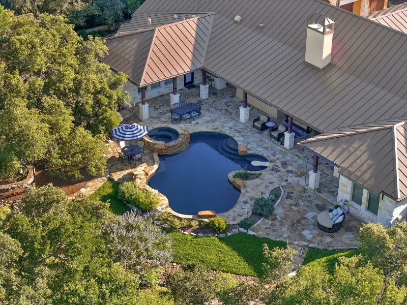 Overhead aerial of freeform pool and spa on flagstone patio with metal roofline. Unique perspective. — Austin real estate photography