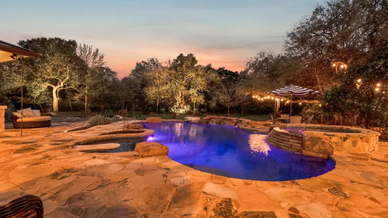 Backyard pool under a purple-and-gold twilight sky. — Austin real estate photography