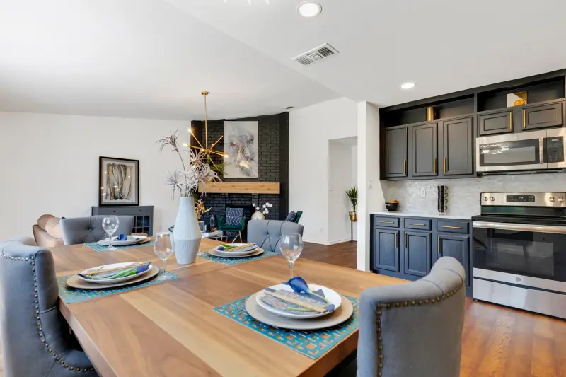 Styled dining table with blue place settings flowing to a fireplace; excellent staging. — Dallas/Fort Worth real estate photography