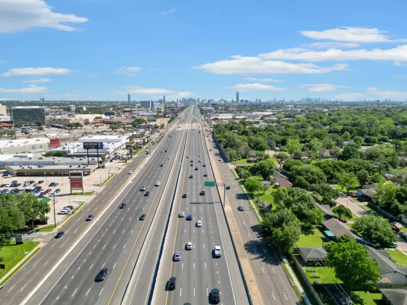 Aerial over highway with distant skyline, strong leading lines and traffic. Editorial drone shot. — Houston real estate photography