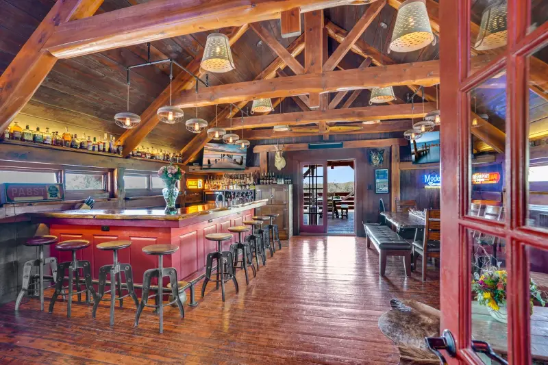 Timber-frame great room and bar with reclaimed wood floors — Austin–San Antonio corridor real estate photography