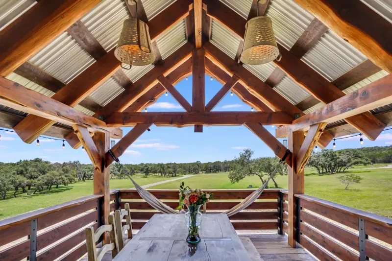 Covered porch framing the Hill Country view over a wood rail — Austin–San Antonio corridor real estate photography
