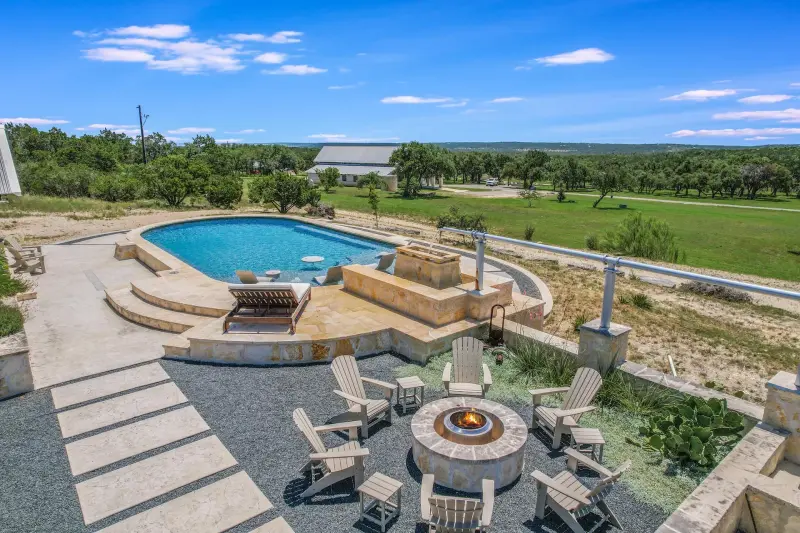 Aerial of the pool terrace and fire pit overlooking Hill Country pasture — Austin–San Antonio corridor real estate photography